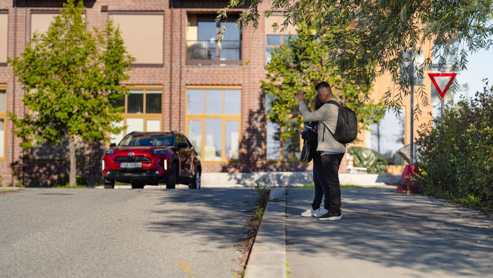 Passasjer vinker til sjåfør i boligområde